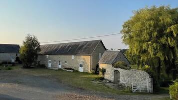 A stone building with a sloped roof, a small attached structure, and a gate.