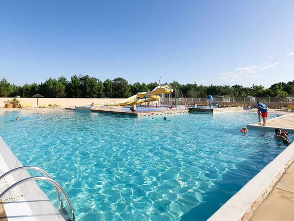 A swimming pool with clear water, a water slide, and a lifeguard stand. - Beach 800 m away | 6/8-person mobile home | Pool & Air Conditioning (Seignosse)