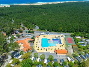 Vista aerea di un resort con piscina, campo da tennis e accesso alla spiaggia.