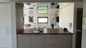 Eine moderne Küche mit einer zentralen Kochinsel, weißen Schränken und Blick in den Wohnbereich.