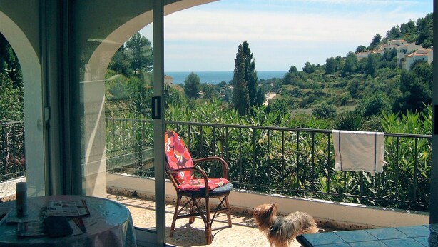 A balcony with a view of a coastal landscape, a chair, and a small table with a newspaper. - Villa with private pool, terrace, in Benissa, CostaBlanca, to rent 7 days  (VC)