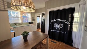 Una cocina con comedor, una puerta negra con el texto 'Rose Apothecary' y una lámpara colgante.