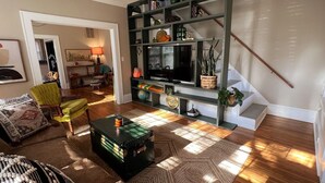 A living room with a green entertainment unit, a green suitcase, and a patterned rug.