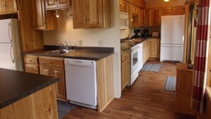 A kitchen with wooden cabinets, a dishwasher, a stove, and a refrigerator. - Aerie - Vermilion Dam Lodge (Orr)