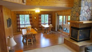 A wooden cabin interior with a dining area, a fireplace, and a stone wall. - Aerie - Vermilion Dam Lodge (Orr)