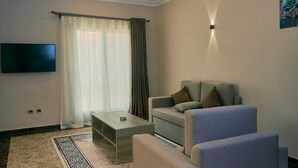 Een moderne woonkamer met een bank, een salontafel en een flatscreen televisie aan de muur.