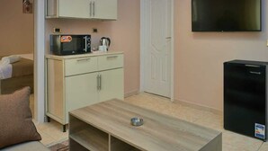 Een knus woongedeelte met een kitchenette, een flatscreen-tv, een koelkast en een bank.