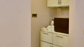Een kleine kamer met een kitchenette, inclusief een fornuis, kastjes en een klein aanrecht.