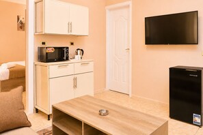 A compact room with a kitchenette, a flat-screen TV mounted on the wall, and a small refrigerator. - Roadhouse New Cairo Residence (New Cairo)
