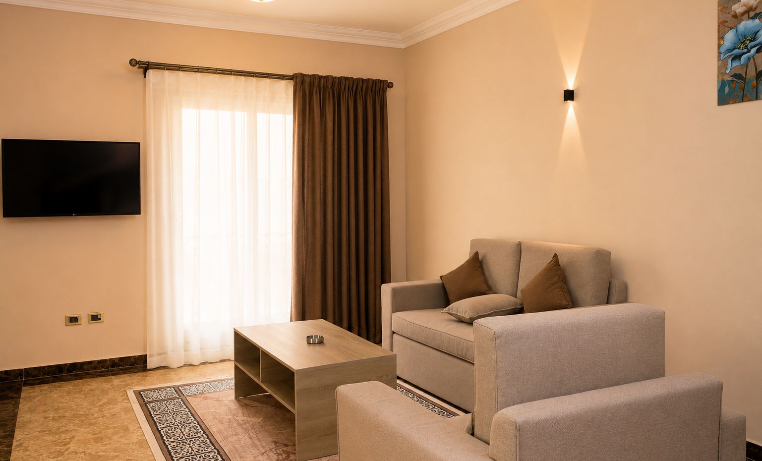 Un salon moderne avec un canapé, une table basse et un téléviseur à écran plat fixé au mur.