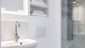 Un baño moderno con cabina de ducha de vidrio, un lavamanos blanco y un inodoro.