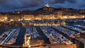 A marina at night with boats docked and city buildings in the background.
