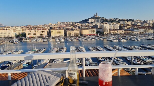 A marina with numerous boats docked, a bottle of Corona Extra beer, and a glass of red drink on a table.
