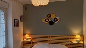 A bedroom with a wooden headboard, two bedside tables with lamps, a bed with white bedding, and a wall decoration above the bed. - 54 m2 apartment 150m from the sea (main beach) and 100m from the village (Damgan)