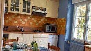 A compact kitchen with a dining table set for four, a microwave, and a window with a view of greenery. - 54 m2 apartment 150m from the sea (main beach) and 100m from the village (Damgan)