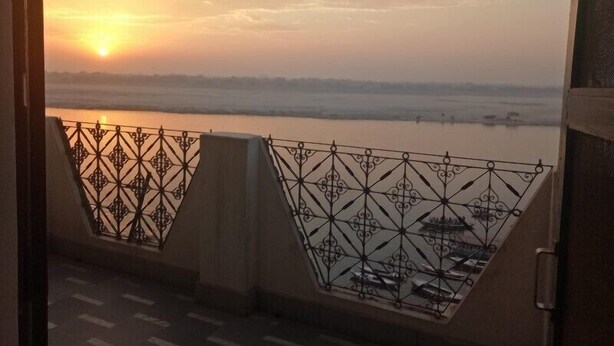 Vista del atardecer desde un balcón con baranda de metal que da al río.