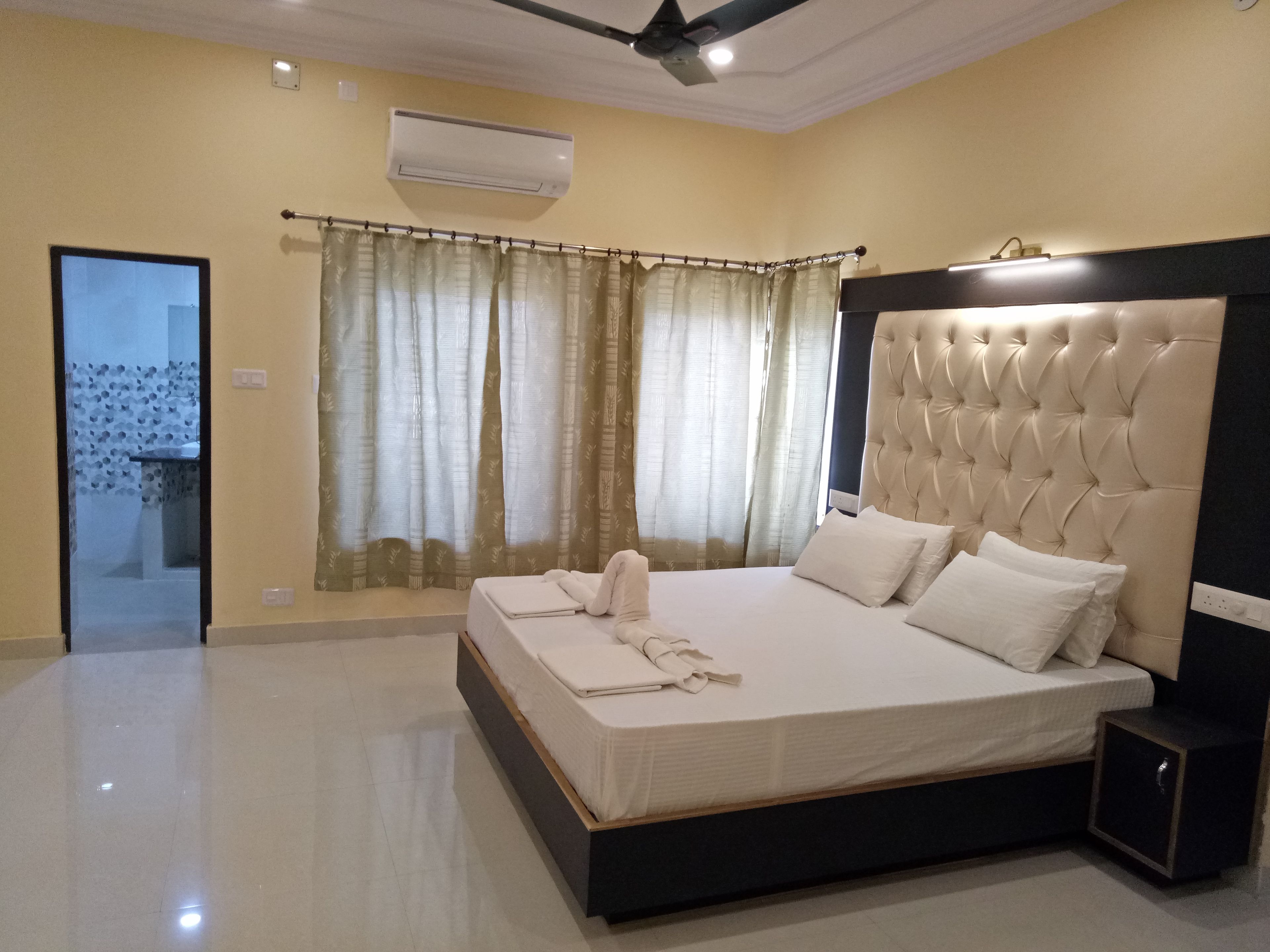A hotel room with a bed, a nightstand, a ceiling fan, and a window with curtains.