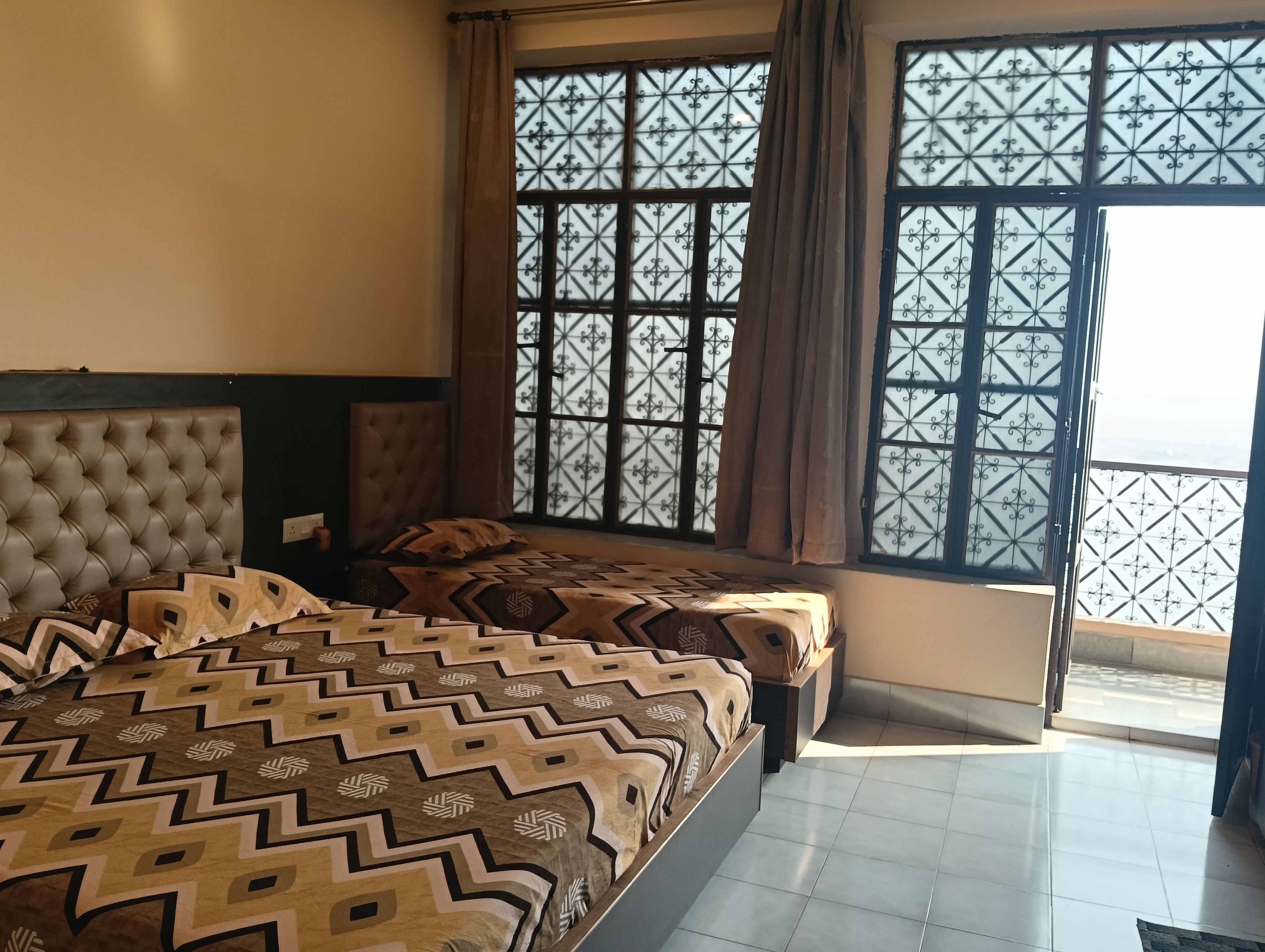 Une chambre à coucher avec un grand lit, deux tables de chevet et une fenêtre ornée de barreaux en fer décoratifs.