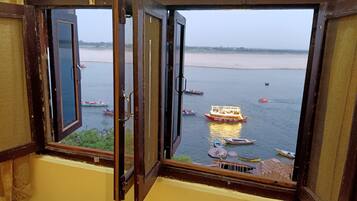 A view through an open window with a view of a river and boats.