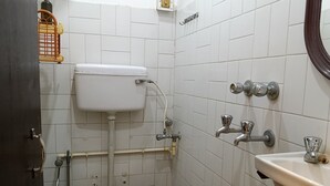Un baño pequeño y sencillo con inodoro, lavamanos y zona de ducha.