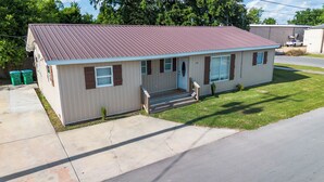 A single-story house with a metal roof, a front porch, and a small front yard.