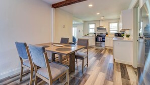 A modern kitchen with a central island, wooden flooring, and a dining area with a table and chairs.