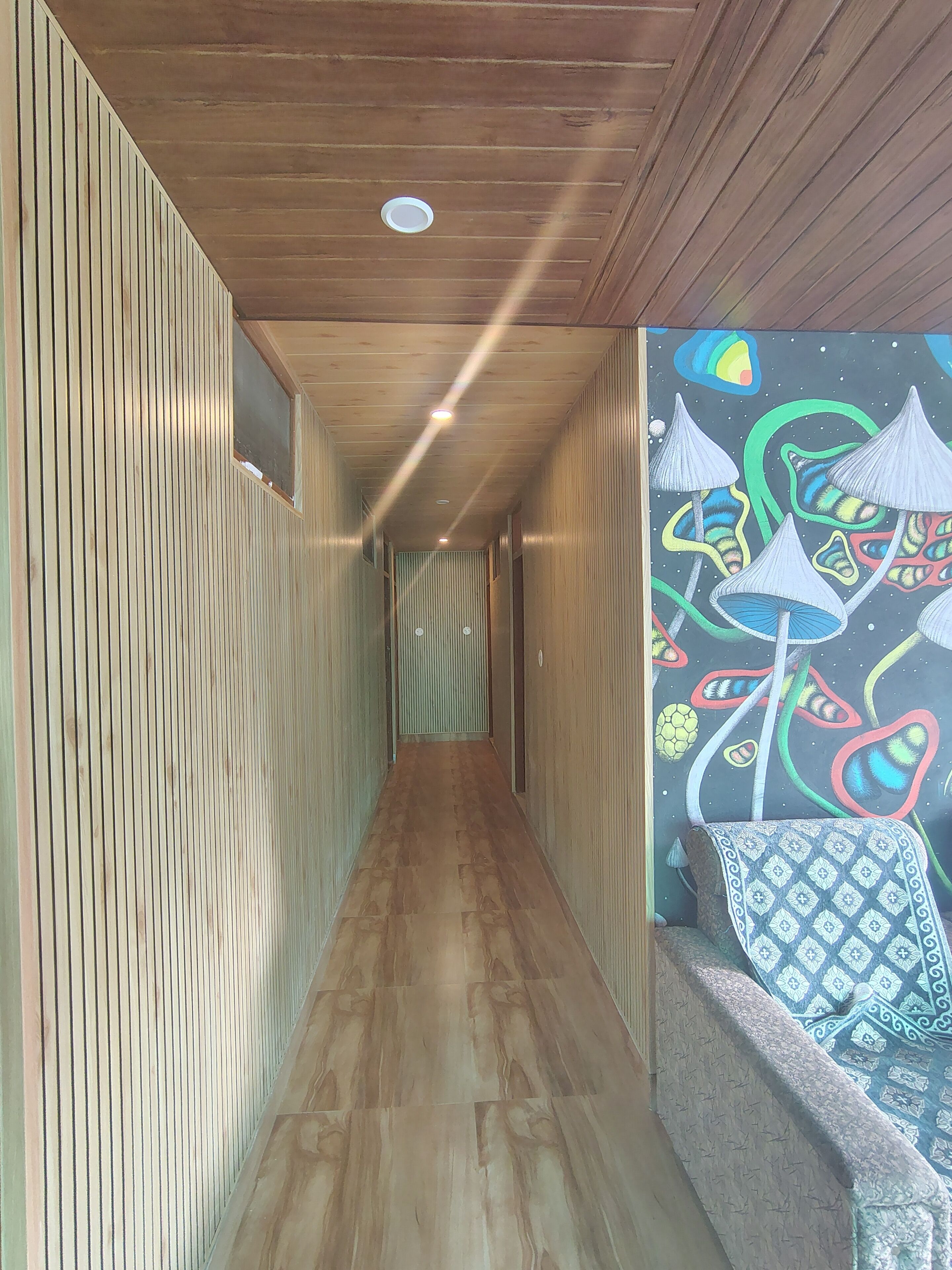 Un couloir aux murs recouverts de lambris en bois, doté d’un sol à motifs et orné d’une fresque colorée sur le mur de droite.