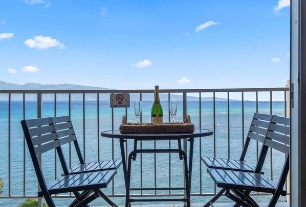 A balcony with two chairs, a table, a bottle of champagne, and a 'No Smoking' sign.