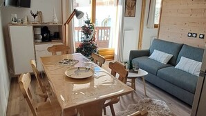 Una sala de estar acogedora con una mesa de madera, un sofá gris y un árbol de Navidad.