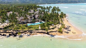 Un complexe hôtelier tropical doté d’une piscine, de palmiers et d’une plage.