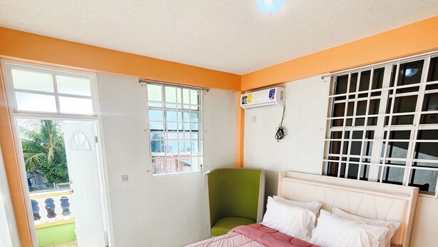 A bedroom with a bed, a chair, and a window. - Elite Island Breeze 2-bed apt in Jimmit, WiFi, AC, Free Parking,Central location (Jimmit)