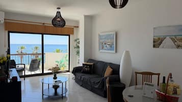 Ein Wohnzimmer mit einer Couch, einem Couchtisch, einem Esstisch und Meerblick durch eine Schiebetür.