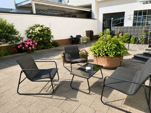 An outdoor patio with metal chairs and a table, surrounded by potted plants and flowers. - To complete (Mönchengladbach)