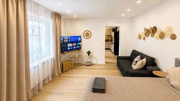 Ein modernes Wohnzimmer mit Fernseher, Sofa und Wandbildern.