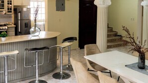 A modern kitchen with a central island, bar stools, and a dining area with chairs and a table. - 4-bedroom luxury villa in tranquil Puerto Plata with WiFi, AC stunning rooftop (Puerto Plata)