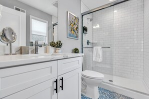 Un baño moderno con tocador blanco, cabina de ducha de vidrio y un inodoro.