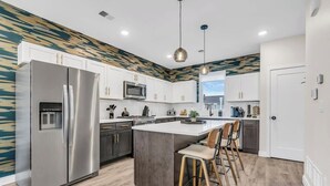 Een moderne keuken met een centraal eiland, roestvrijstalen apparatuur en een decoratieve spatwand.
