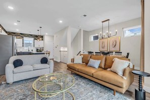 A modern living room with a sofa, coffee table, and dining area.