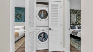Een kleine wasruimte met twee gestapelde wasmachines, een witte deur en een modern interieur.