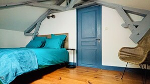 A bedroom with a sloped ceiling, a bed with blue bedding, a wooden floor, and a blue door. - Pretty house in the historic district of Cahors close to shops (Cahors)
