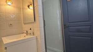 A bathroom with a white sink, a glass shower enclosure, and a blue door. - Pretty house in the historic district of Cahors close to shops (Cahors)