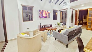 Un salón amplio con un sofá, una mesa de centro y un televisor montado en la pared.