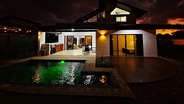 Una casa moderna con piscina, patio e interior bien iluminado.