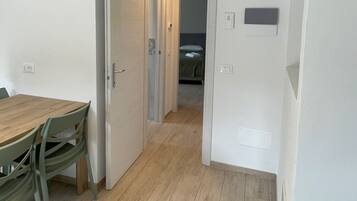 Un pasillo con piso de madera que conduce a una habitación con cama y mesita de noche.