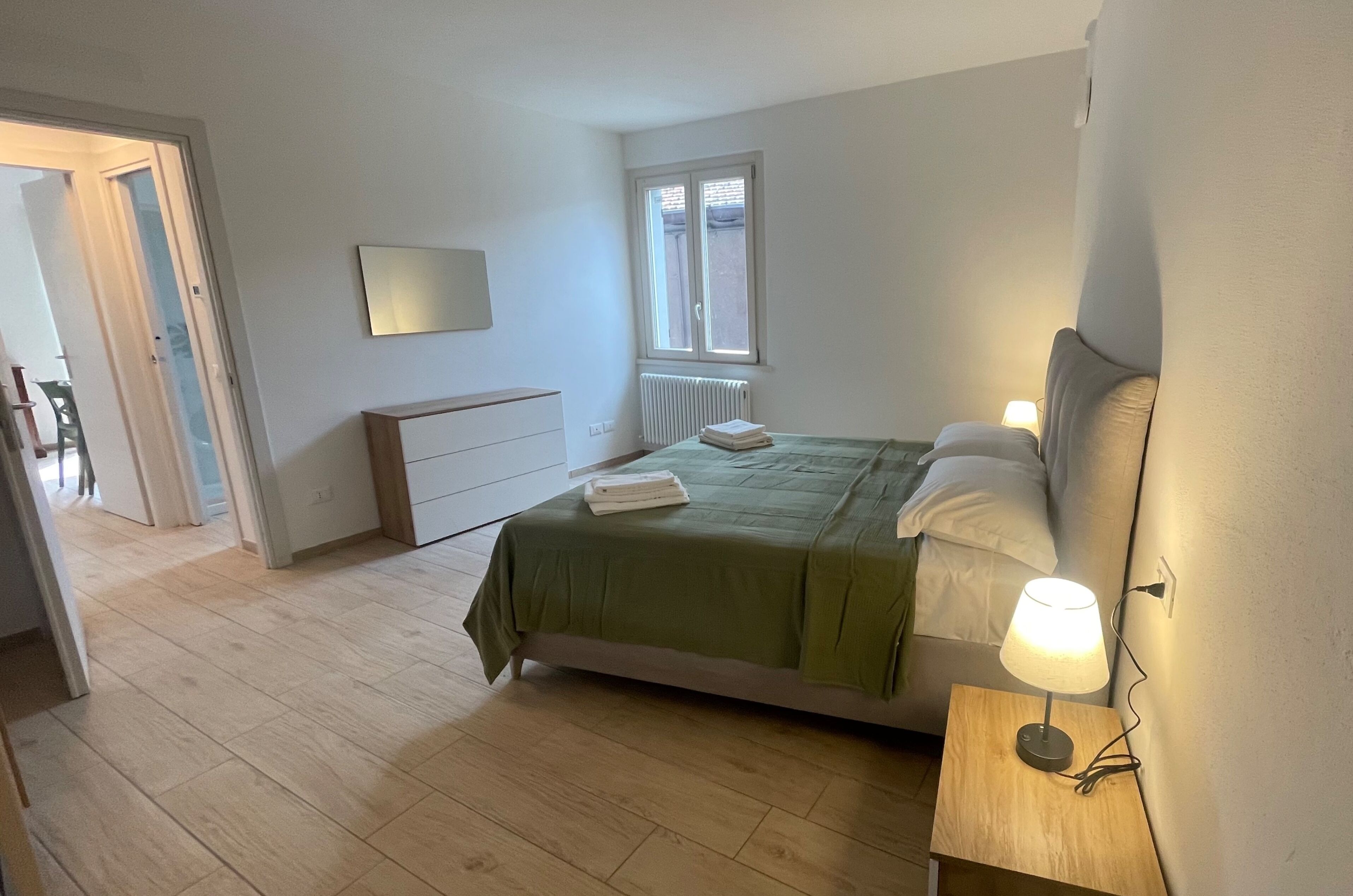Un dormitorio con cama, lámpara de noche y ventana.