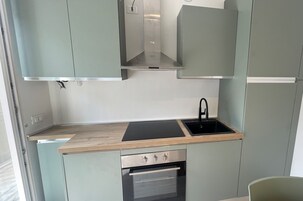 Una cocina compacta con horno empotrado, pileta y extractor de acero inoxidable.