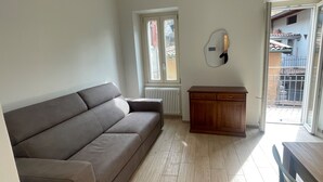 Un salon comprenant un canapé, un meuble en bois et une porte-fenêtre coulissante donnant sur un espace extérieur.