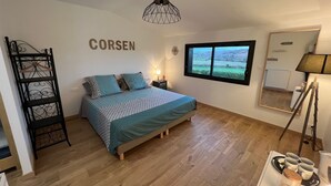 Et soveværelse med seng, lysekrone, et vindue med udsigt og et spejl på væggen.