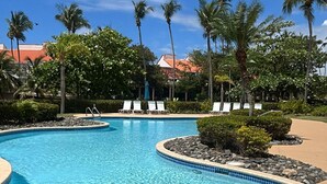 A clear blue pool with lounge chairs and palm trees in the background.