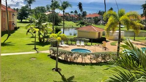 A resort with a pool, palm trees, and a small building.